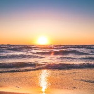 Experience the serene sunset over Ludington Beach with vibrant colors and tranquil waves.